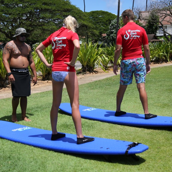couple standing on soft top surfboards during dry land training