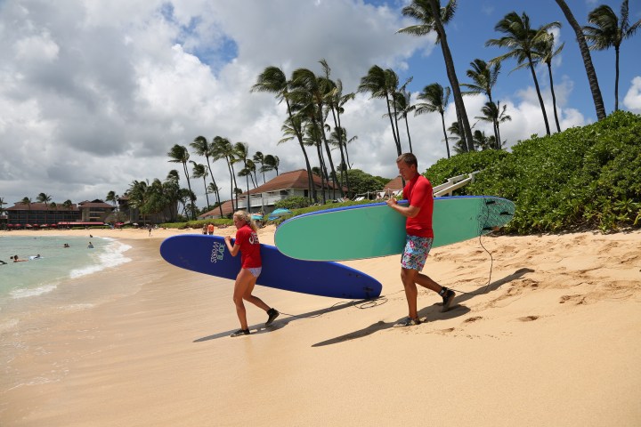 couple holding surfboards while ankle attachments walking to the ocean preparing to surf