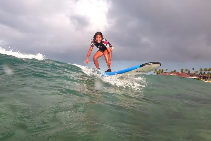 girl surfing over the crest of a wave in kauai