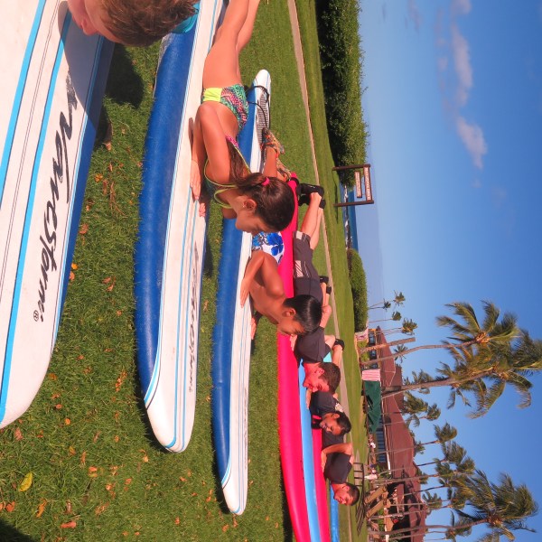 group of kids on dry land learning to surf in Kauai