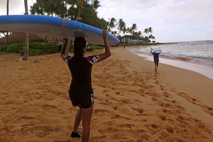 women holding surfboards on their heads
