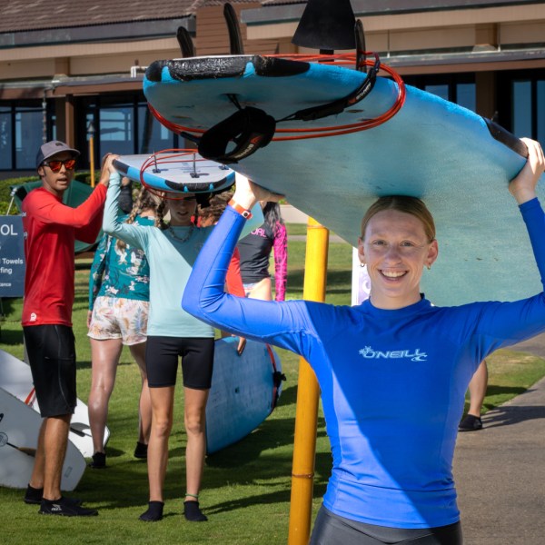 a women carrying her surfboard on top of her head