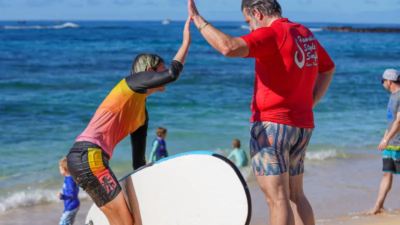 a couple high fiving after a surf lesson in kauai