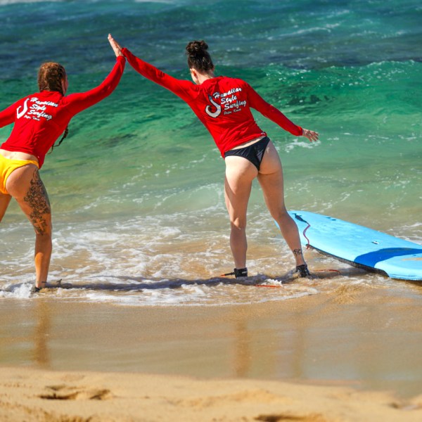 two girls giving each other high fives after a surf lesson in poipu hawaii